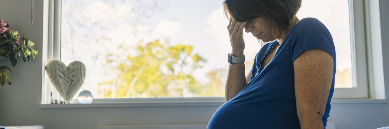 The Long-Term Health Impact of Preeclampsia During Pregnancy Mature pregnant woman sitting on her bed feeling ill.