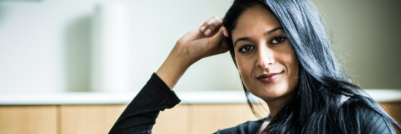 How Lying From Anxiety Made Me Lose My Identity South Asian woman subtly smiling and looking ahead