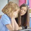 photo of young woman offering support in school to upset girl