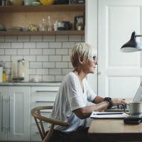 Older woman with short white hair sitting at a home desk, working remotely