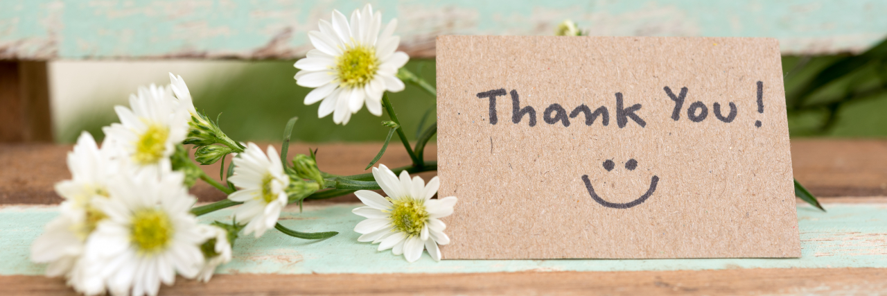 hank you note with smile face and flower cluster on wooden chair