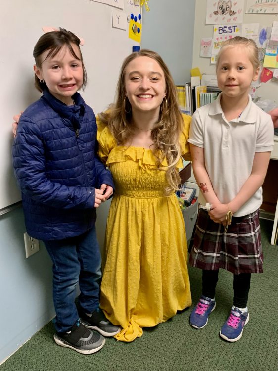 The author's children stand with a teacher in a classroom.