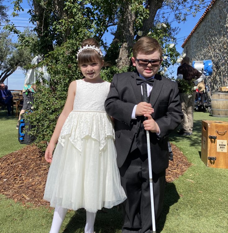 Karl wearing a tuxedo and holding his cane, next to on-screen sister played by Sophia Sawaya