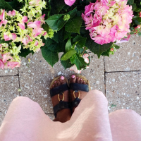 A photo of the bottom of someone's dress, and their open toed shoes. Parallel to them is some pretty pink hydrangeas.