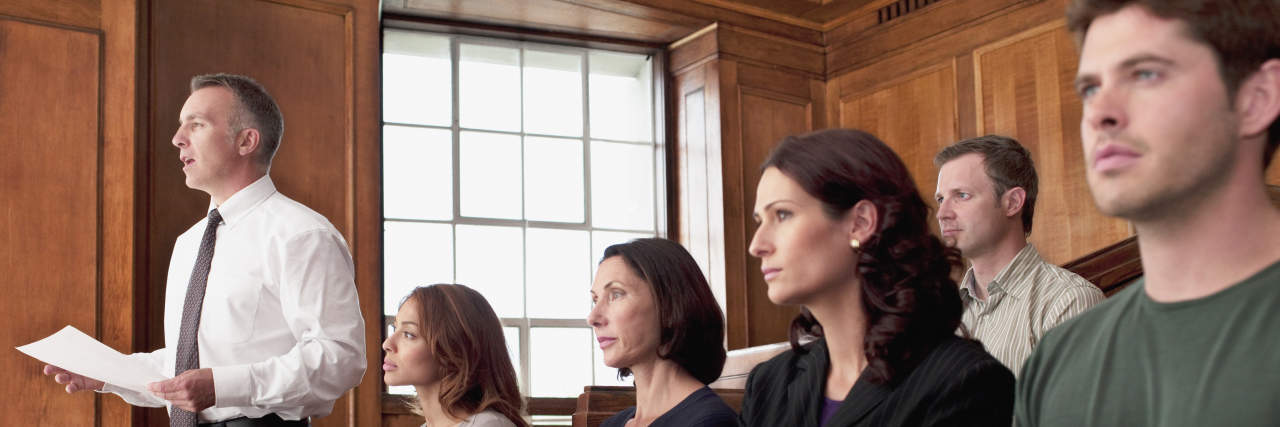 A jury sits in the jury box of a courtroom.