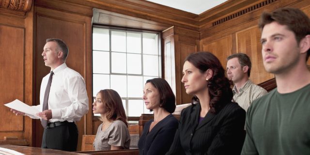 A jury sits in the jury box of a courtroom.