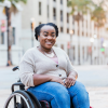 Black woman, smiling and using a wheelchair outside in city