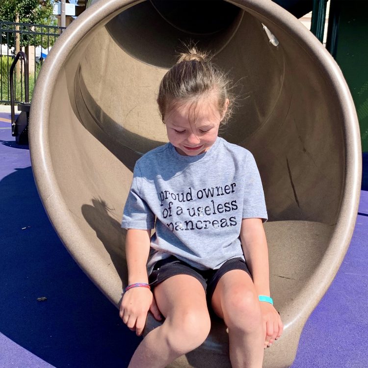 Young girl sitting at bottom of slide at playground