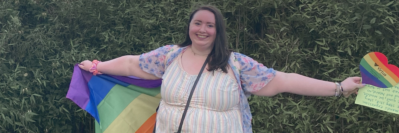Fighting Anxiety by Attending My First Pride Parade Contributor standing with her arms out holding rainbow flags