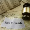 Roe v Wade news headline with gavel on a copy of the United States Constitution.