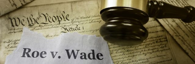 Roe v Wade news headline with gavel on a copy of the United States Constitution.