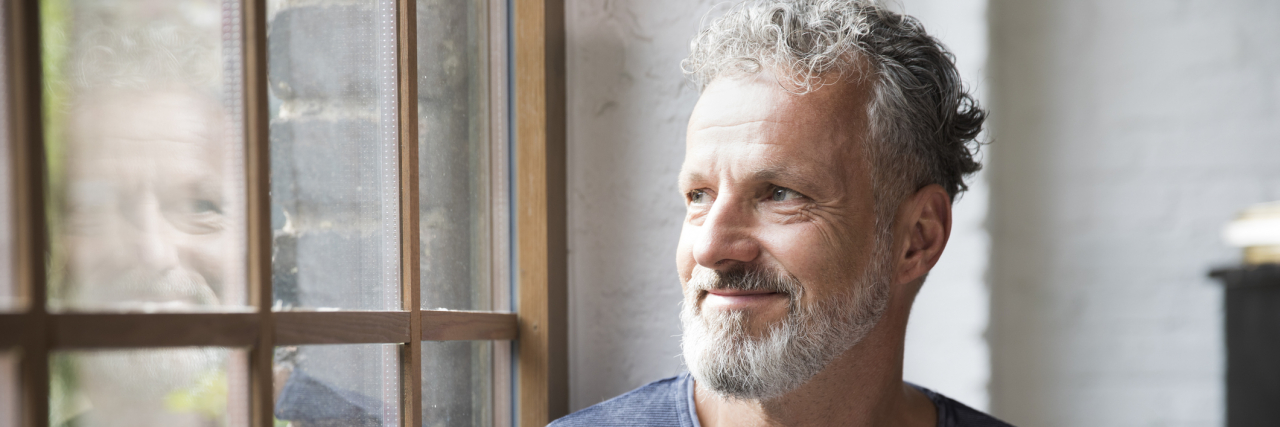 What It's Like To Live With the Unpredictability of Parkinson's Mture man taking a break, drinking coffee at the window of his loft apartment