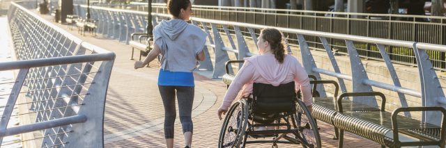 ng woman with spina bifida, and a friend on a city boardwalk.