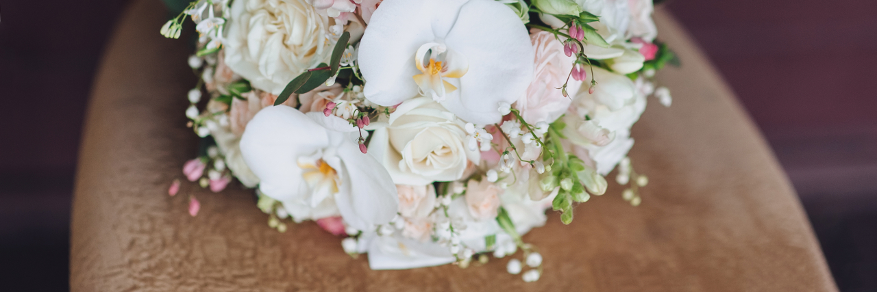 Wedding bouquet on a vintage chair. Orchid, rose. Country style. Close-up.