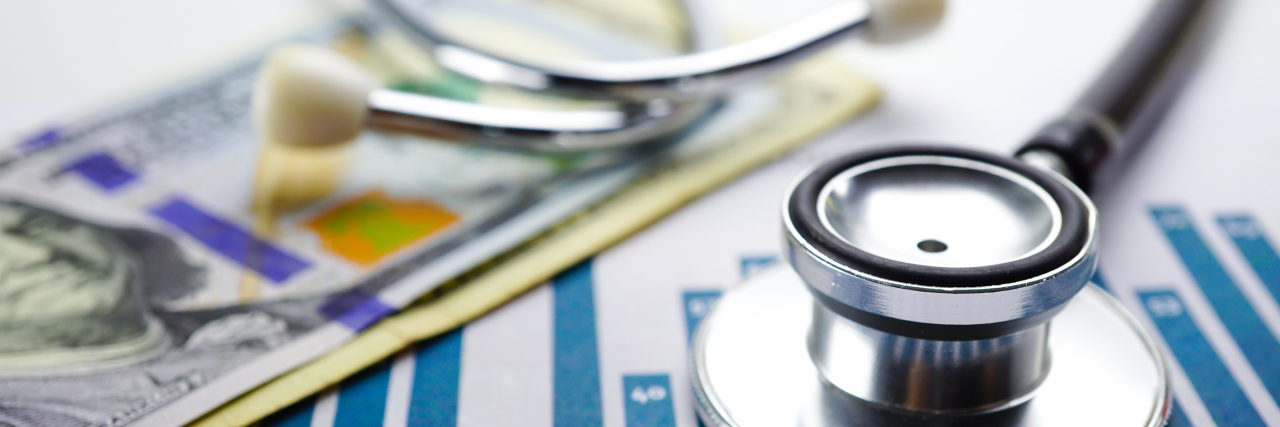 Is Medical Debt Causing You Anxiety? Here's Some Good News Stethoscope and US dollar banknotes on chart.