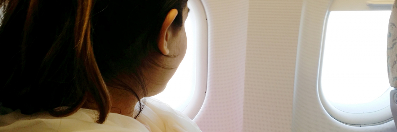 Travel Hacks if You're an Anxious Flier photo of a person looking out of an airplane window