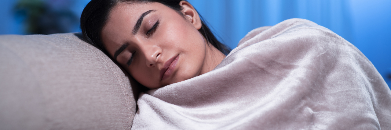 11 Anxiety Relief Products to Always Have in Your House phioto of a young woman wrapped in a blanket