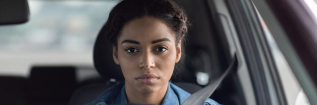 A black woman holding a steering wheel staring intently ahead of her