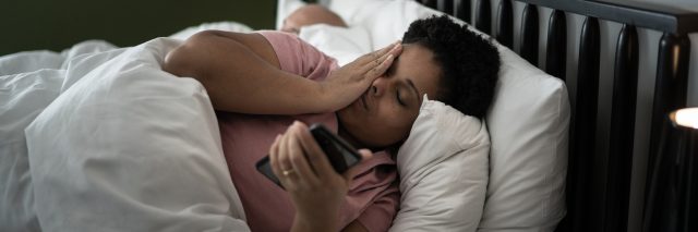 Woman in bed checking smartphone