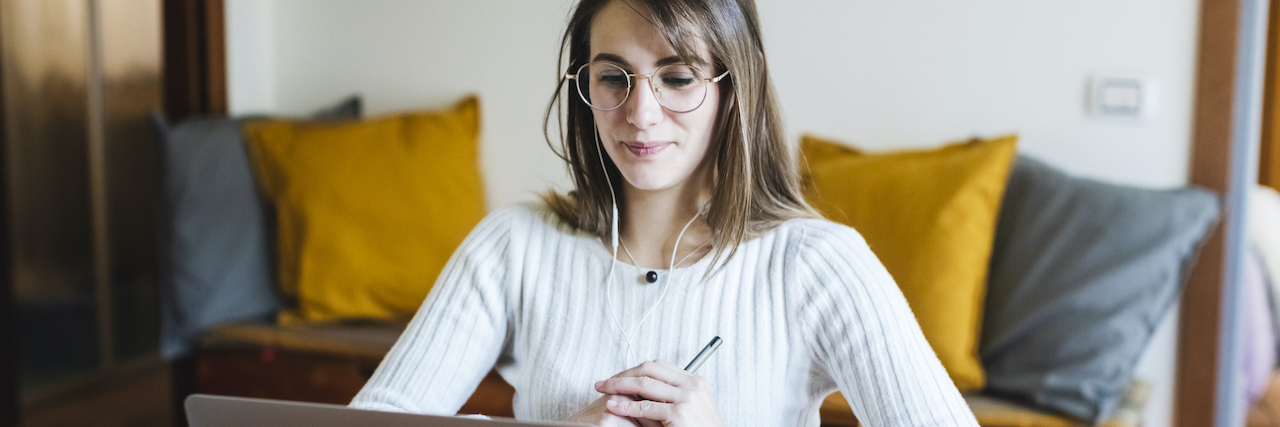Woman studying at home with laptop and headphones