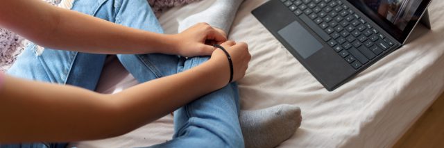 girl has psychotherapy session with her therapist via video call. She has rubber band on her wrist to prevent anxiety.