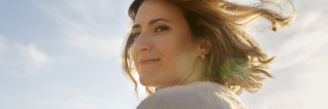photo of a young woman looking back over her shoulder at sunset and smiling