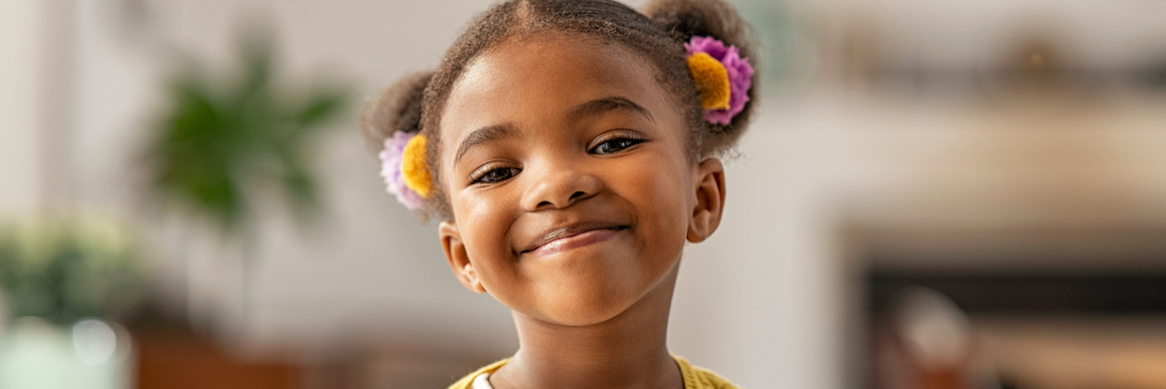 Young Black girl smiling and with her hair in pig tails