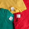Three colorful t-shirts with blank labels.