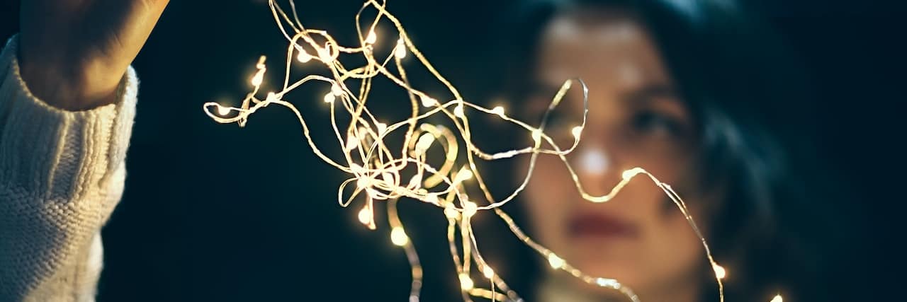 Woman holding string of small lights blurring in front of her