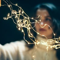 Woman holding string of small lights blurring in front of her