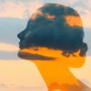 Double exposure of woman's face, clouds and sunset glow