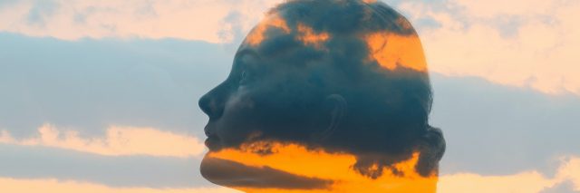 Double exposure of woman's face, clouds and sunset glow