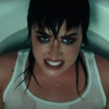 Demi Lovato sitting in a bathtub wearing a white tank top with dark makeup on her face