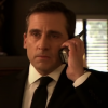 Michael Scott from "The Office" taking a phone call in a suit in a dimly lit room.