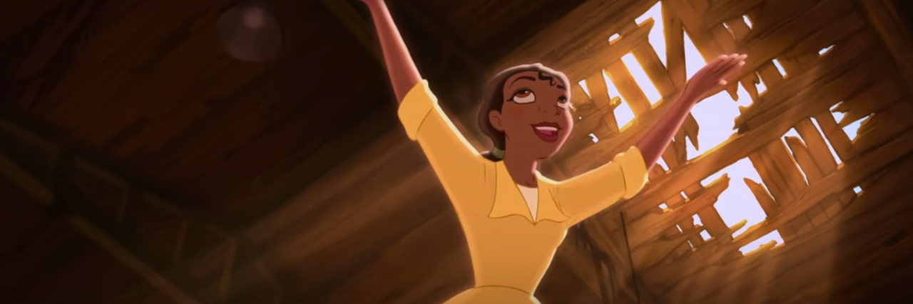 What Your Favorite Disney Princess Says About Your Mental Health Tiana from Disney's "The Princess and the Frog." She has her arms raised towards the sky and is wearing her yellow waitress dress in the old sugar mill that she wants to make her restaurant.