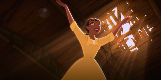 Tiana from Disney's "The Princess and the Frog." She has her arms raised towards the sky and is wearing her yellow waitress dress in the old sugar mill that she wants to make her restaurant.