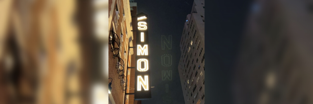 Neil Simon theater at night in New York City with a blurred out version of the same photo behind it.