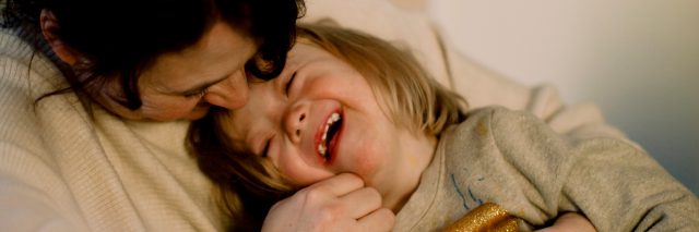 A mother holds her smiling daughter with Down syndrome.