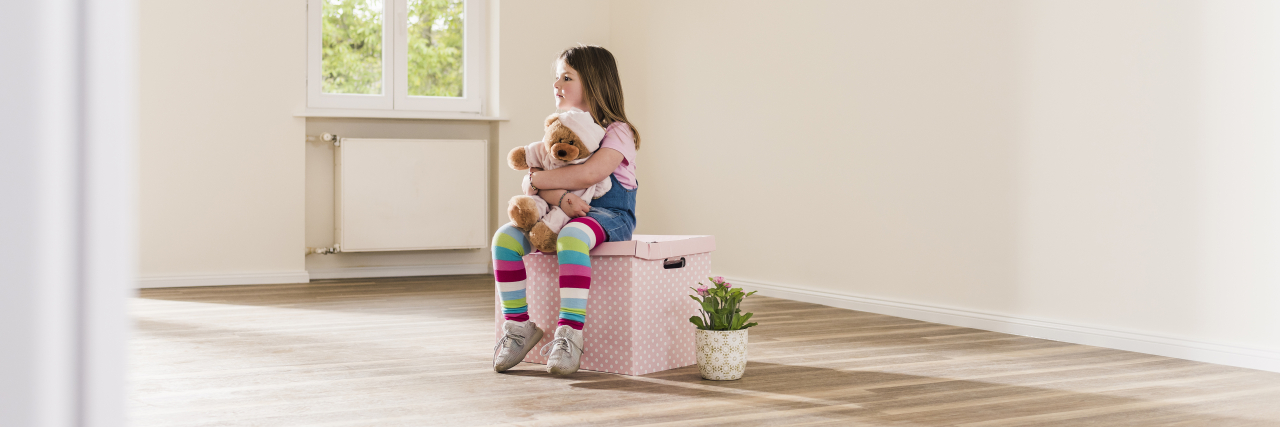 Feeling Trapped and Finding Yourself With Addison's Disease A young girl sits on a pink box in an empty apartment.