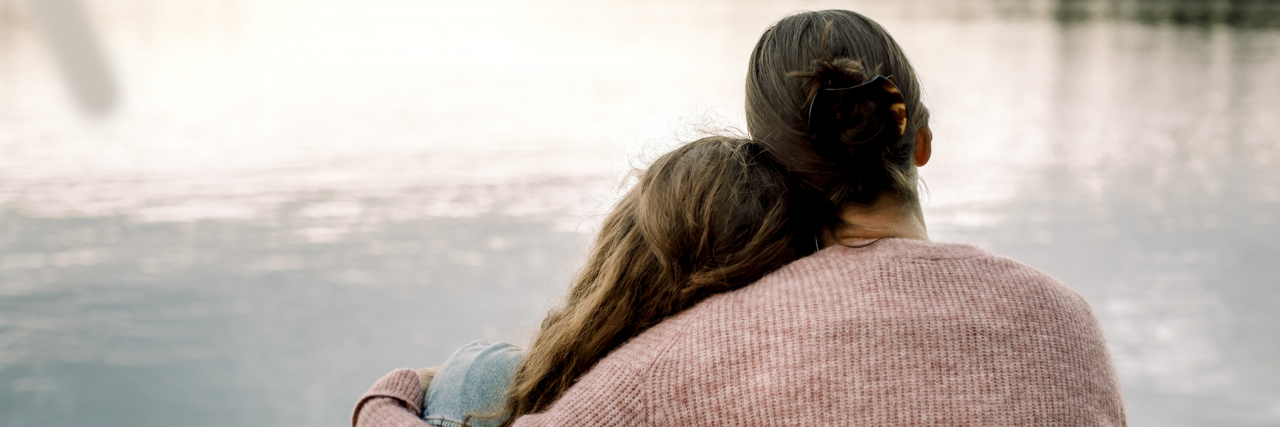 Healing Your 'Inner Adolescent' as an Adult A woman with brown hair in a bun and wearing a sweater hugs a teenage girl with long, wavy hair.