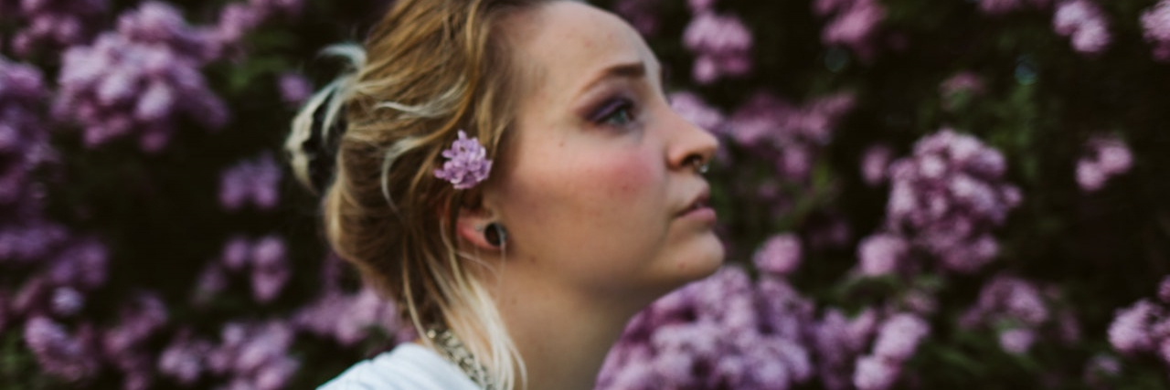 What It's Like to Lose a Friend You Met in Eating Disorder Treatment Profile of a woman standing in front of violet flowers