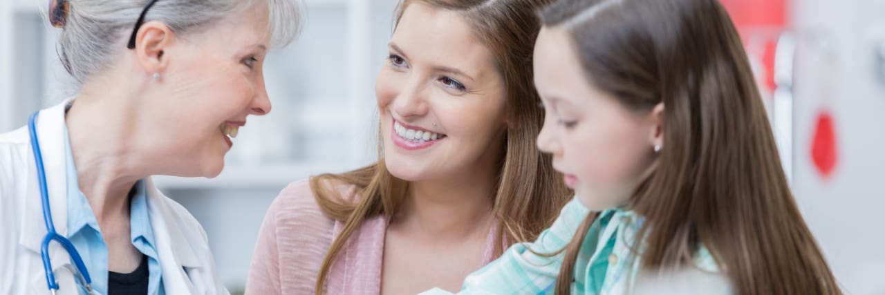 Lessons I Learned Parenting a Child With Type 1 Diabetes A female doctor takes a young girl's blood sugar levels as the girl's mom watches.