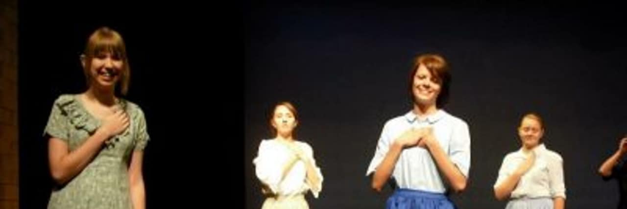 Reactions When Your Chronic Illness Is Shared Without Your Permission The author stands on stage with the cast of a musical.