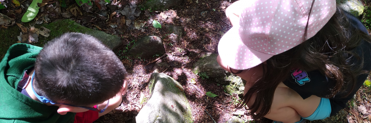 Embracing Small Moments While Parenting a Child With a Rare Disease The author and her child examine an object on the ground outside.