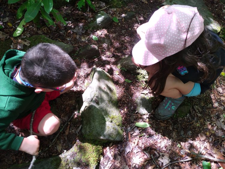 The author and her child examine an object on the ground outside.