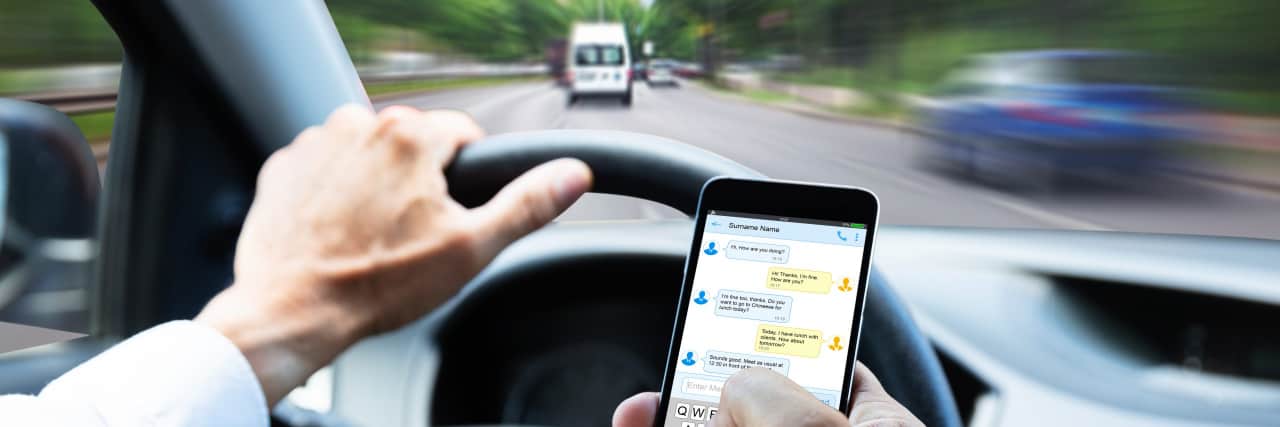 How Distracted Drivers Can Endanger Someone With a Spinal Cord Injury Man texting while driving