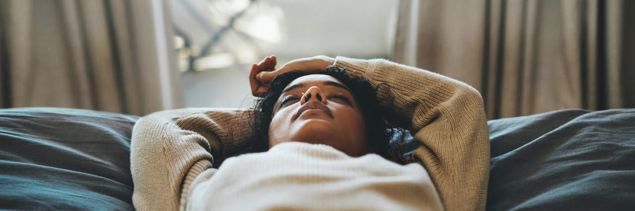 Cropped shot of a young woman lying on her bed with her eyes closed