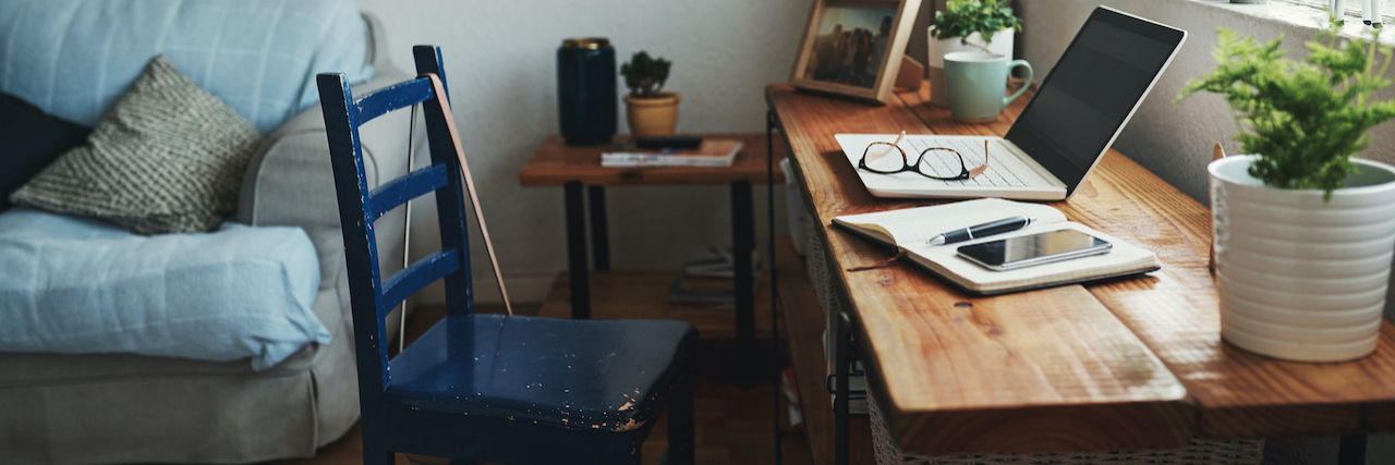 Retiring for My Mental Health and Grieving the Loss of My Profession Laptop, glasses and a notebook on desk with an empty chair in front of it