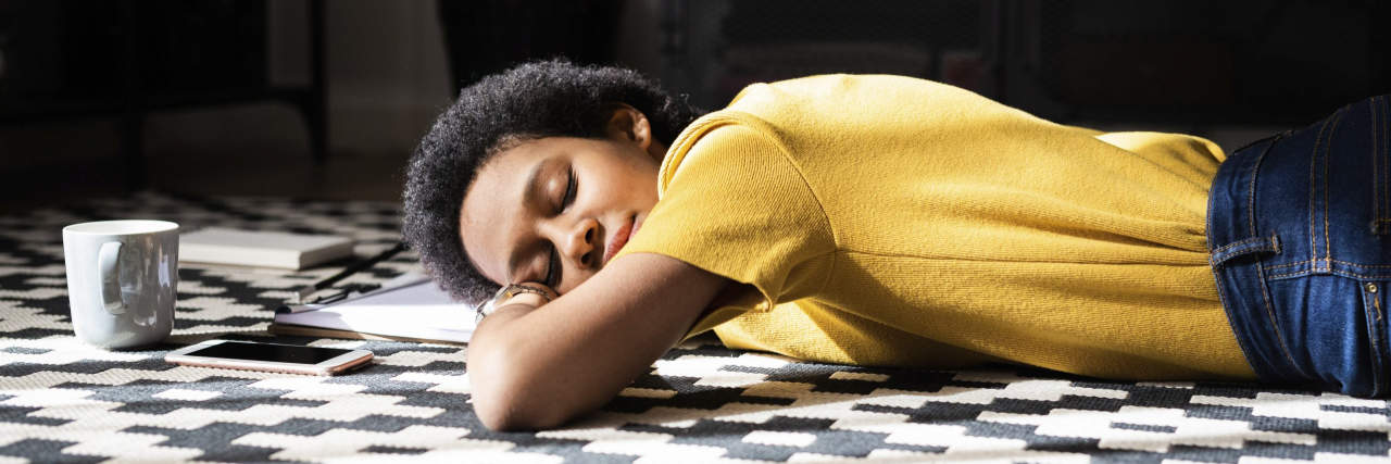Person lying on the floor at home with closed eyes
