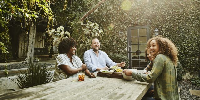 Why Relationships Matter With NMOSD Laughing family sharing meal at picnic table in backyard